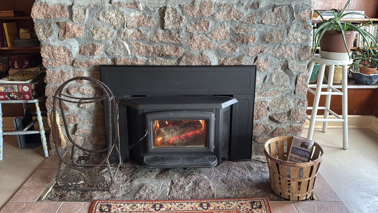A fire burning in a wood stove insert set into a stone fireplace