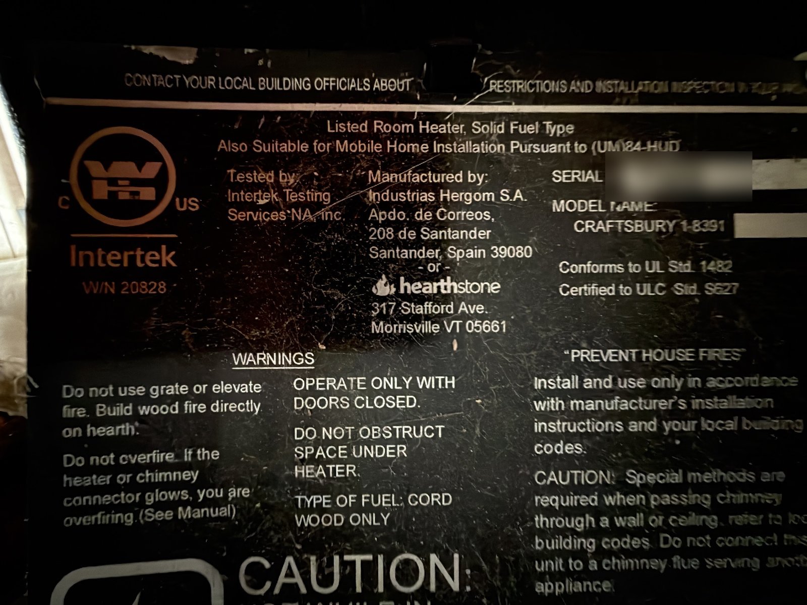 The certification label on a wood stove, listing it as a solid fuel room heater certified to ULC S627, the label that sets how close the stove can sit to a wall