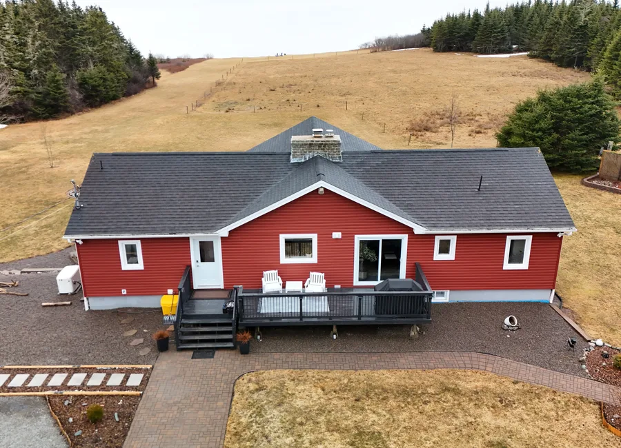 Drone view of a red single storey home with a hip roof and stone chimney in St. Martins, New Brunswick